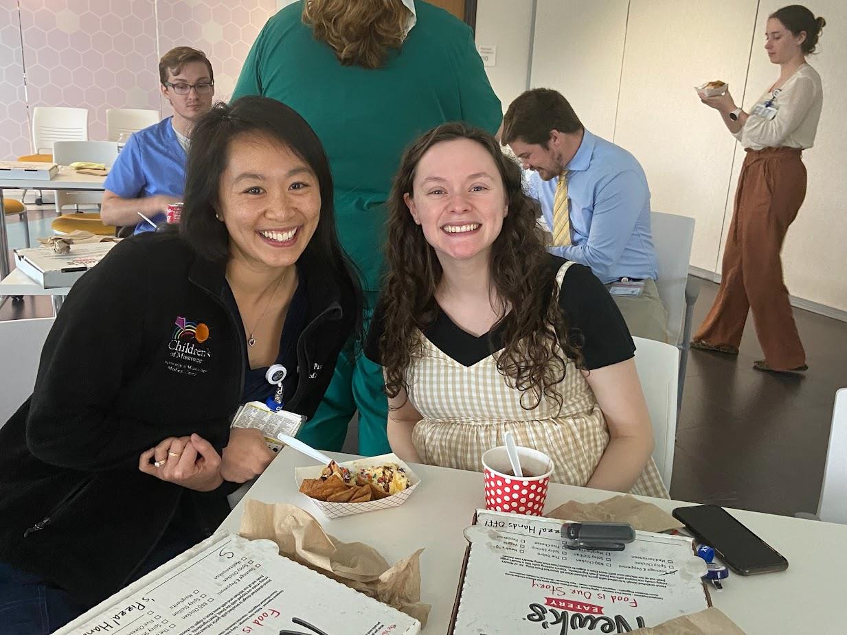 two pediatric residents sitting at table at indoor event